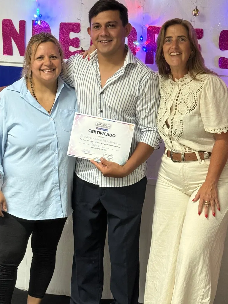 Un egresado muestra su certificado acompañado por su capacitadora y por Cecilia Gortari